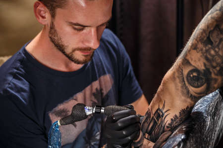 Close up tattoo artist demonstrates the process of getting black tattoo の写真素材
