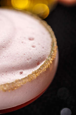 Refreshing alcoholic cocktail with egg foam in a glass rimmed with brown sugarの写真素材
