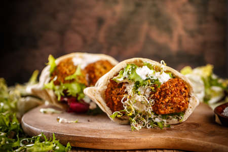 Falafel balls in pita with tahini sauce on wooden boardの写真素材