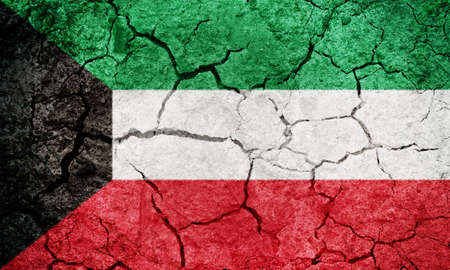State of Kuwait flag on dry earth ground texture backgroundの写真素材