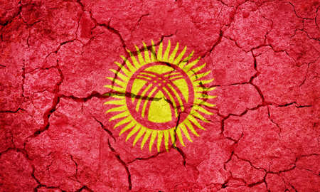 Kyrgyz Republic flag on dry earth ground texture backgroundの写真素材