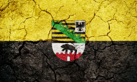 Saxony-Anhalt, state of Germany, flag on dry earth ground texture backgroundの写真素材