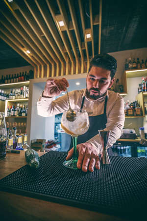 Bartender is stirring cocktail on the bar counterの写真素材