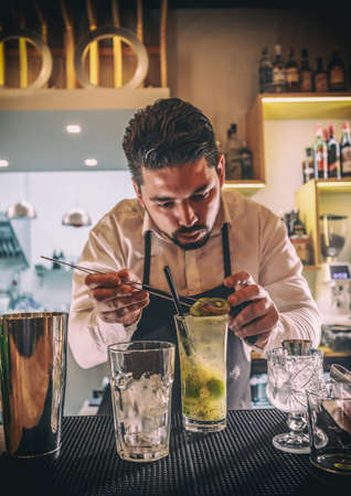 Bartender decorating cocktail with kiwiの写真素材