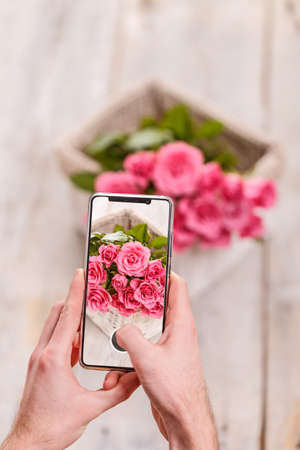 Man taking photo of Rose flower with mobile phone の写真素材