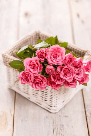 Still life with pink roses in wicker basketの写真素材