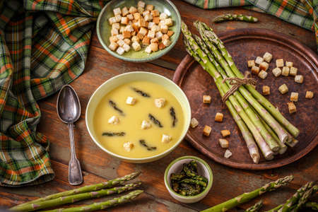 Asparagus cream soup served with croutons on wooden backgroundの写真素材