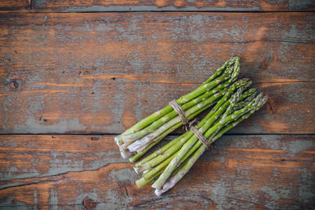 Top view of fresh asparagus bunches on rustic wooden backgroundの写真素材