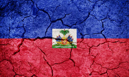 Republic of Haiti flag on dry earth ground texture backgroundの写真素材