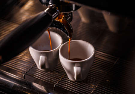 Professional espresso machine pouring strong looking fresh coffee into a ceramic cupの写真素材