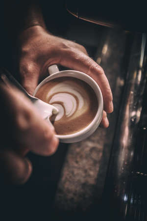 Barista pours milk making cappuccino or latte art. Toned pictureの写真素材