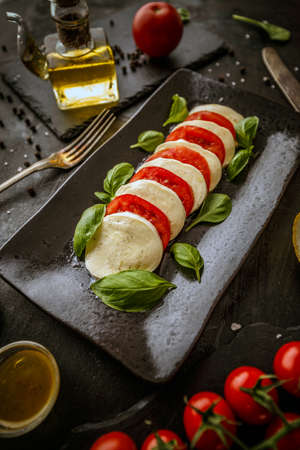 Delicious caprese salad with ripe tomatoes, mozzarella cheese and fresh basil leaves. Italian food.の写真素材