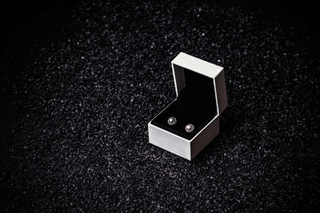 Pair of earrings with pearl in white box on black backgroundの写真素材