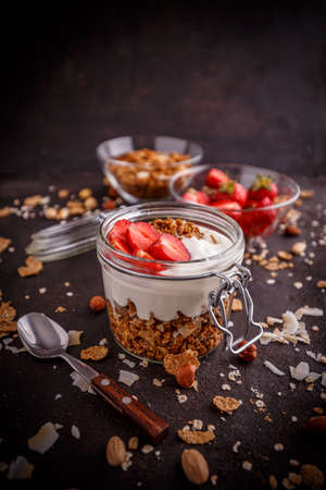 Homemade granola in glass jar layered with yogurt and fresh strawberriesの写真素材