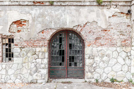 Old door and broken window on weathered brick buildingの写真素材