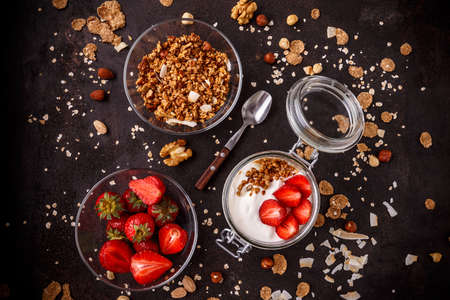 Tasty granola with yogurt and fresh strawberries on black backgroundの写真素材