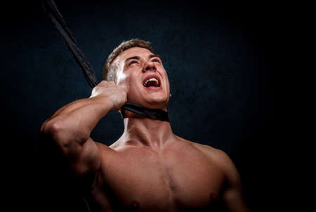 Someone pulling back a shirtless muscular man tieの写真素材