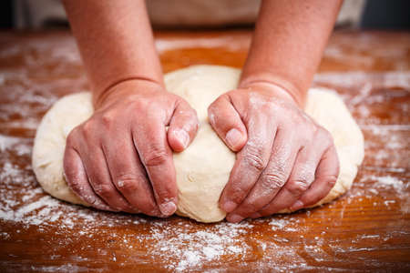 Female hands preparing dough for pizza on table closeup