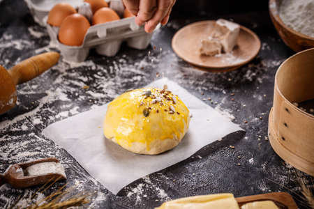 Sprinkling mix of seeds over homemade bunの写真素材