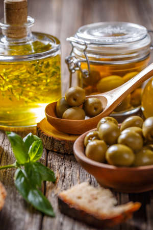 Green olives and olive oil on wooden backgroundの写真素材