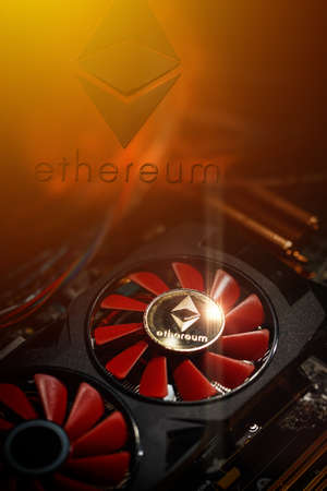 Cryptocurrency mining concept closeup with golden ethereum on top of a computer performant video card red fansの写真素材