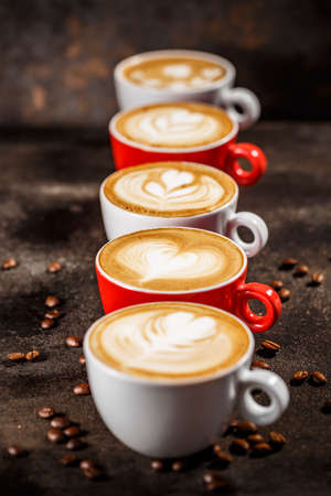 Many cups of cappuccino with latte art on dark backgroundの写真素材