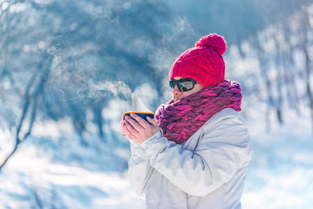 Portrait of the woman with steaming hot tea in snowy winterの写真素材