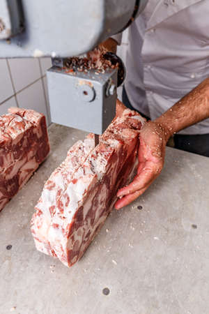 Industrial food processing machine cutting frozen pork chopsの写真素材