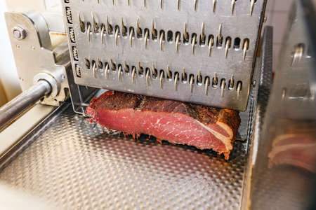 Meat cutter with ham in meat factoryの写真素材