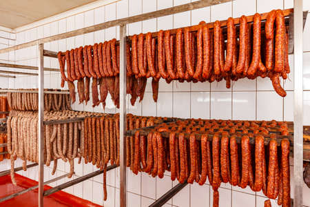 Stick of salami are smoked on the background of the meat factoryの写真素材