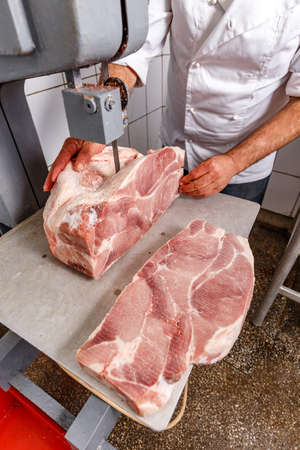 Butcher work's concept, he cuts frozen pork meatの写真素材