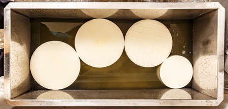 Young cheese-wheels in the water bath. Process of creates protective and preserving layerの写真素材