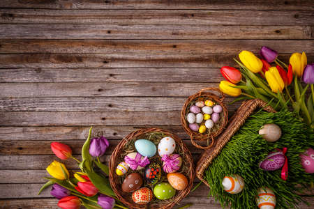 Easter eggs and tulips on wooden planks with space for text