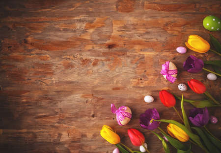 Easter greeting card with eggs and tulips on wooden background. Top view with space for your...