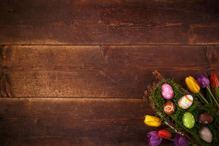 Easter greeting card with eggs and tulips on wooden background. Top view with space for your...