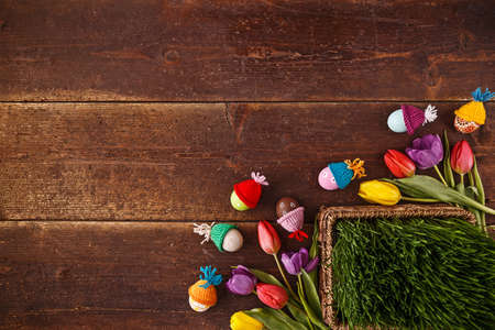 Easter eggs, green grass and tulips on old wooden background, copy space