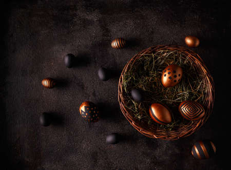 Black and gold eggs over black background. Flat lay