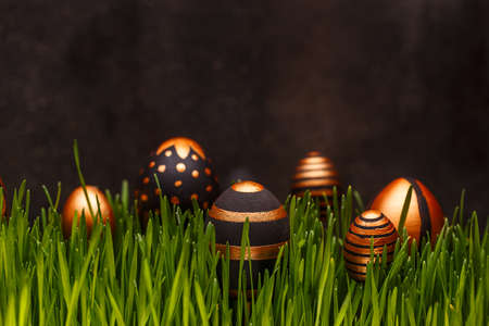Easter background. Easter eggs in various golden designs hiding in green grass