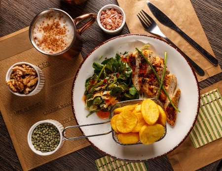 Flat lay of fried chicken fillet and fresh vegetable salad serveed with fried potatoes