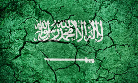 Flag of the Kingdom of Saudi Arabia on dry earth ground texture backgroundの写真素材