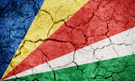 Republic of Seychelles flag on dry earth ground texture backgroundの写真素材