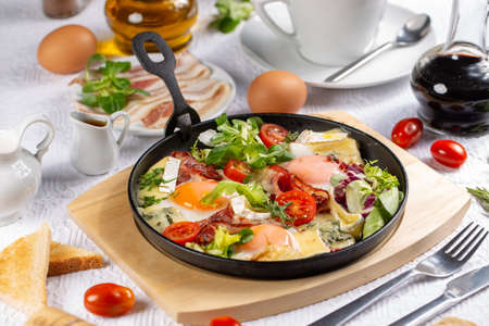 Restaurant delicious breakfast with sunny side up fried eggs, bacon, topped camembert and greens