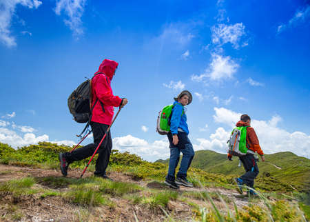 Family with backpacks hiking on summer vacation in mountainsの写真素材