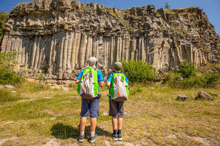 Boys with backpacks looking at columnar basalt lava rock formation