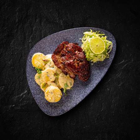 Grilled mangalica pork chop served with creamy potatoes in butter and iceberg lettuce with limeの写真素材
