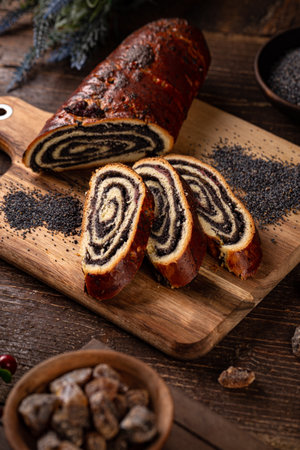 Traditional Hungarian beigli roll with poppy seed filling slices on a wooden boardの写真素材
