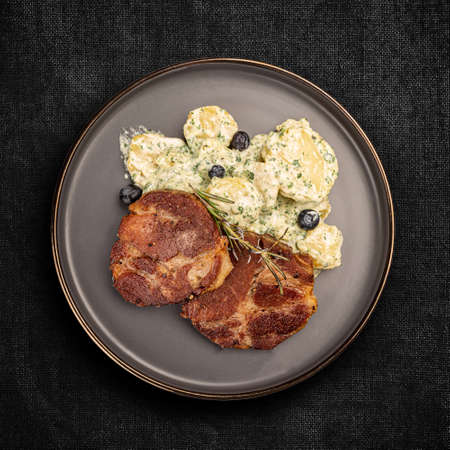 Juicy grilled pork chop served with potato salad, top view, flat layの写真素材