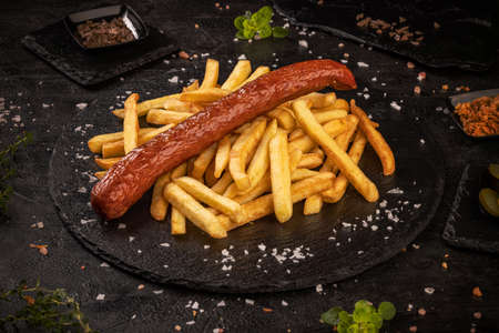 Grilled pork sausages served with french fries on black slate backgroundの写真素材