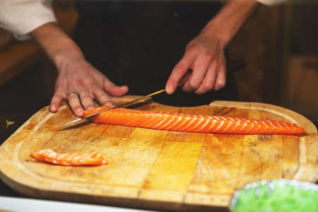 Chef cutting salmon fillet on the wooden cutting boardの写真素材