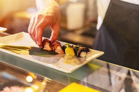 Chef serving traditional japanese sushi served on a white plate.の写真素材